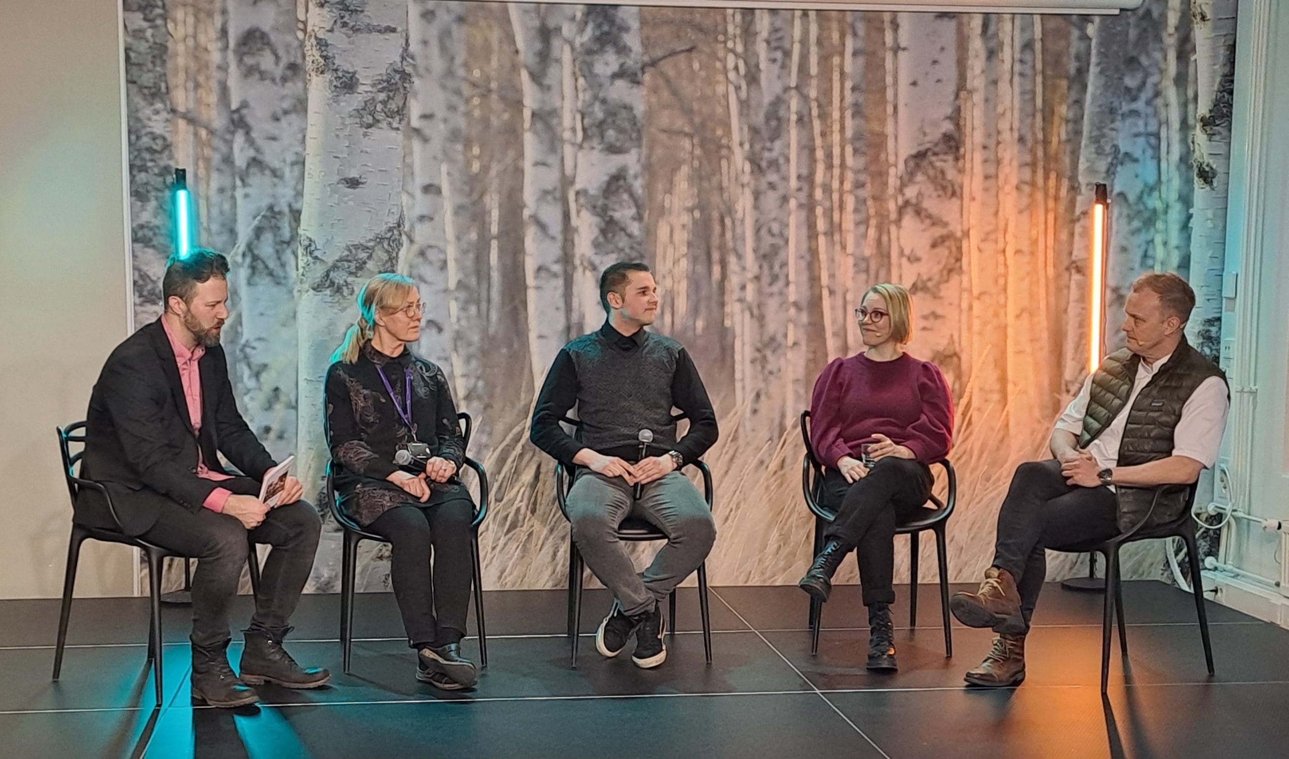 Kuvassa viisi henkilöä istumassa vierekkäin tuoleilla paneelikeskustelussa.