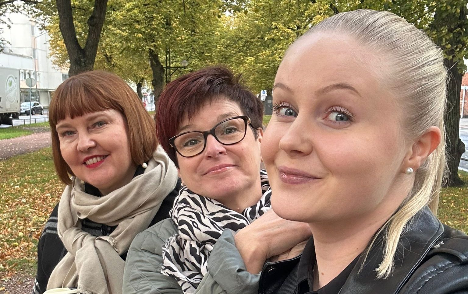 Kolme naista hymyilemässä kuvassa tiiviisti vierekkäin ollessaan.